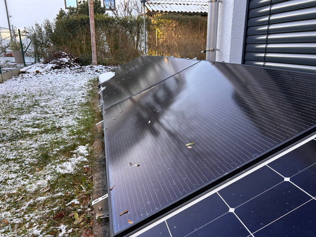 Solarmodule auf einer niedrigen Aufständerung neben einem Haus im Winter
